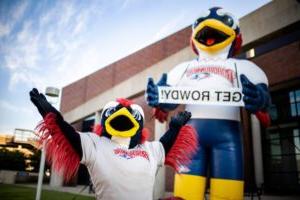 Mascot Rowdy cheers with his arms up besides an inflatable Rowdy with a sign that says Get Rowdy